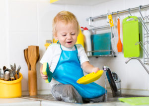 Kid child boy washing dishes and having fun in the kitchen